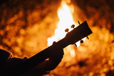 Gitarist kız dışarıda şenlik ateşi yakınında gitar çalıyor. Ateşin yanında arkadaşlarla vakit geçirmek, gitar çalmak.