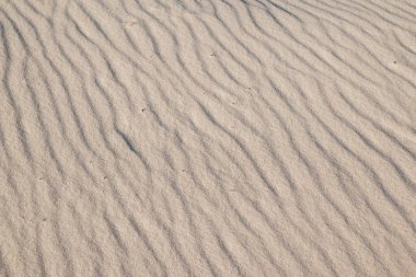 Sahildeki dalgalı kum dokusunu kapatın. Denizde ya da nehir kıyısında tatil, yazın dinlenme ve boş zaman kavramı.
