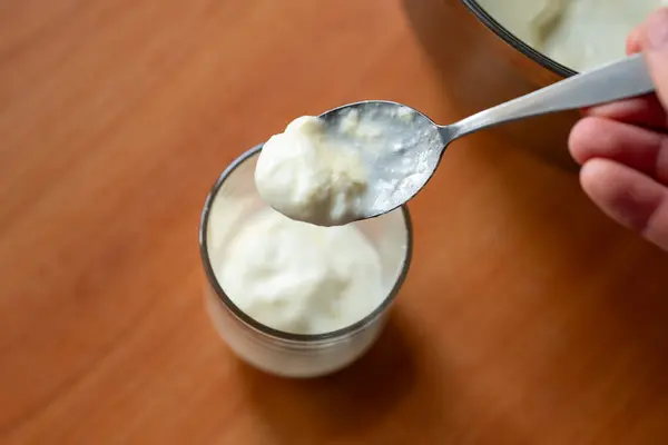 Erkeğin elindeki kaşığı ve arka plandaki camı kapat. Süt ürünleri, sağlıklı gıda ve beslenme kavramları