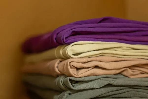 Clean folded t shirts in wardrobe. Stack of clothes in wardrobe