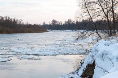 Yüzeyinde pek çok buz parçası akan bir nehir. Kışın nehir, su yüzeyinde buz