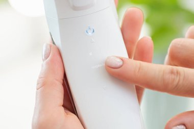 Kadın eliyle ultrasonik deri temizleyiciyi kapat. Kozmetik cihazında 