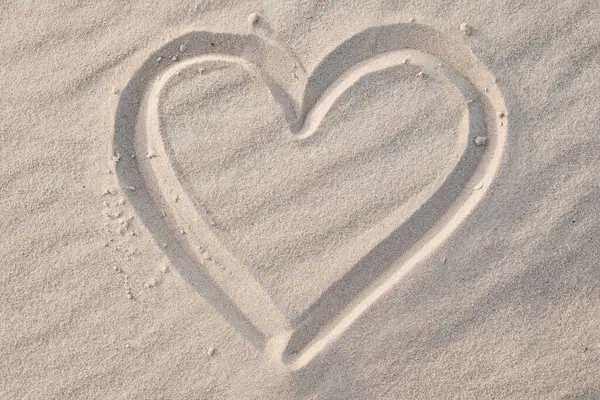 Close up of shape of heart drawn on wavy sand. Concept of love, positive emotions, passionate feelings