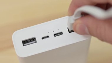 Adam, yüksek kapasiteli güç bankasından kabloyu fişten çekip çıkarıyor. Elektrik cihazlarını şarj etmek için güç bankası kullanılıyor