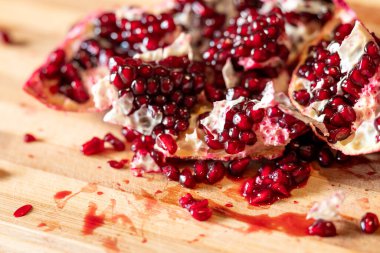 Nar, masanın üzerinde yatarken birçok parçaya bölündü, kapat. Sağlıklı sulu meyve, kırmızı tohumlar, lezzetli organik yiyecekler.