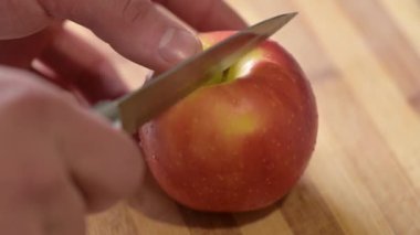 Erkek, kesme tahtasında elmayı ikiye bölüyor. Taze meyve yemek sağlığınız için yararlıdır.