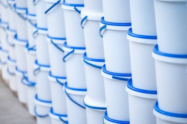 Mavi kapaklı beyaz plastik kovalar. Bir sürü büyük kova, açık hava, toptan satış ve ticaret konsepti.
