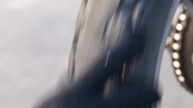 Adam eski lastiği olan bir motosikletin arka tekerleğini çeviriyor. Motosikletin arka lastiğin değiştirilmesi gerekiyor.