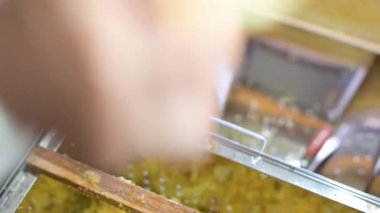 Arı yetiştiriciliği yaparken, bal toplarken. Arı avcısının çerçeveyi balla açması için elektrikli bıçak ve bal çıkarmak için özel çatal kullanması