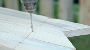 Tahta kalasta elektrikli matkap teçhizatıyla delik açmak. Ahşap çit inşa etmek, çitin bir parçası olarak tahta hazırlamak.