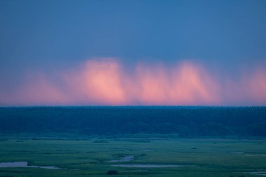 Yağmurlu bulutların parlak sabah manzarası ve arkasında kırmızı ışık var. Kırsalda yağmurlu bir sabah, gün doğumunda canlı renkler