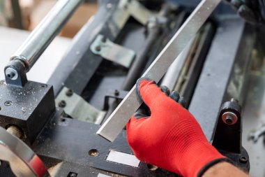 Yeni keskin bıçaklı eldivenli bir marangoz. Profesyonel marangoz, kesim için marangozluk makinesine yeni bir bıçak yerleştiriyor.