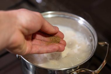 Biber kokarken biberli hamuru tencerede buharlaştırmak. Pişirme sırasında lezzetlerini arttırmak için bir el biber sosu kaynayan hamur köftesine serpiştirir.