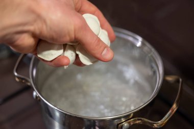 Tencerede hamur köftesi kaynatmak lezzetli ve rahatlatıcı bir yemek yaratır. Bir el kaynar suya hamur köftesi atar, buhar yaratır ve lezzetli bir yemek için beklenti yaratır.