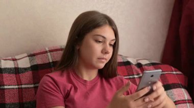 Evde telefonu tutan hayal kırıklığına uğramış genç kız. Genç bir kız telefonuyla koltukta oturuyor, sinir bozucu ve hayal kırıklığıyla tepki veriyor, muhtemelen telefonunun gecikmesinden ya da teknolojik sorunlarından dolayı. Her gün gençlik hayatı