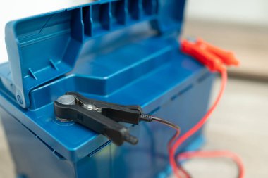 Şarj aleti kullanarak araba aküsünü şarj etmek. Evin içinde şarj olan bir araba aküsünün yakın çekim görüntüsü. Araç bakımı, enerji arzı ve pil bakımı kavramı