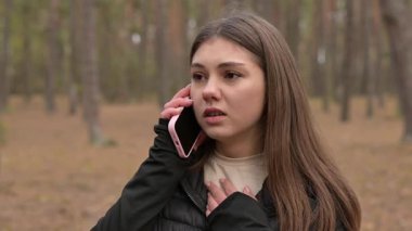 Genç kız ormanda duygusal bir telefon görüşmesi yaparken umutsuzluğa kapılır. Genç bir kız ormanda bir telefon görüşmesi yapmak için duruyor. Umutsuzluğu ve üzüntüyü açıkça ifade ediyor.