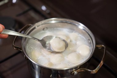 Kaynar suda karıştırılmış pelmeni kaşığı. Bir kaşığın yakından çekimi pelmeni 'nin kaynayan bir tencerede hazır olup olmadığını kontrol ediyor, köfte pişirmenin son aşamasını gösteriyor.