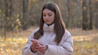 Genç kız sonbahar ormanındaki mesajdan sonra korkar. Genç kız sonbahar ormanlarında yürüyor, korkutucu mesajlar okuyor ve etrafa korku içinde bakıyor.