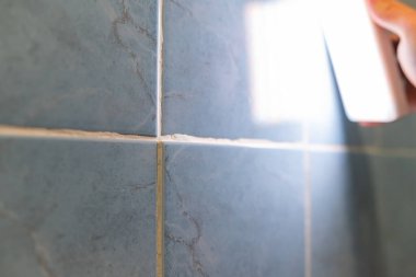 Bir odaya kusurlu döşeme döşemek. Düzensiz döşenmiş kiremitlerin yanlış dizilmiş harç hatlarıyla yakın çekimi, kötü kalitede bir inşaat çalışması olduğunu gösterir