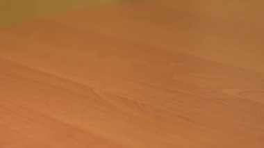 Parlak bir odada yumuşak bir bez kullanarak ahşap bir masadan toz silmek. Bir insan temiz bir bezle pürüzsüz bir ahşap masadan toz temizler.