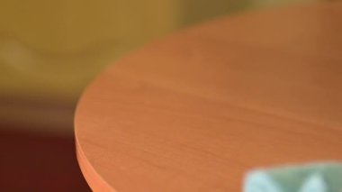 Parlak bir odada ahşap masa yüzeyindeki tozu silmek. Bir insan titizlikle bir bez parçasıyla ahşap bir masanın yüzeyini temizler, temizlikten sonra paçavranın üzerinde çok fazla toz gösterir.
