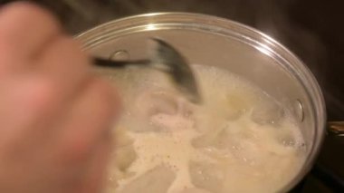 Kaynayan tencerede hamur köftesinin hazır olup olmadığına bakıyorum. Dikkat, özen ve yemek pişirme sürecinin sembolü olan sıcak sudan kaşıkla hamur köftelerini kontrol etmek