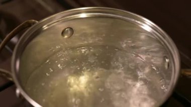 Pişmeden önce gaz ocağında haşlanmış su. Gaz ocağında çelik bir tencerede kaynamış temiz su pişirme sürecinin başlangıç aşaması hazırlık ve beklentinin sembolü.