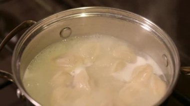 Yemek pişirirken baharat ekleyip mantı karıştırıyorum. Baharatlar kaynar suda pişmiş hamur köftesine eklenir, sonra yavaşça karıştırılır.