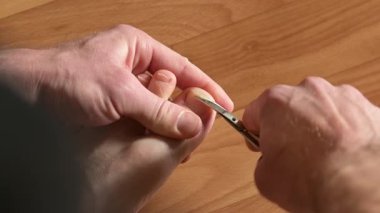 Metal makasla tırnaklarını kesen bir adam. Tırnak makasıyla tırnaklarını kesen bir adamın yakın çekimi. Kişisel bakım, hijyen ve rutin bakım kavramı