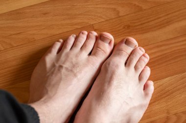 Ahşap zeminde taze pedikür yaptıran erkek ayakları. Zeminde yeni yapılmış pedikür ile bakımlı, temiz erkek ayakları.