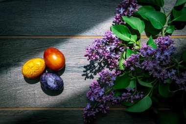 Kırsal bir ahşap zeminde Paskalya yumurtaları ve leylak çiçekleri
