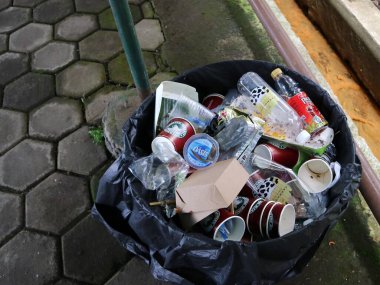 Bandung - Endonezya, 16 Ekim 2022. Çöp yığını plastik, siyah çöp şişesi ve bardak yüzen markette çöp kutusunun içinde..