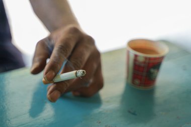 Bir adam elinde sigara tutuyor..