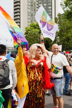 Londra, İngiltere. 02 Temmuz 2022. Londra 'da Gurur Geçidi. Yüksek kalite fotoğraf. Drag Queen, elinde bayraklar olan iki adam için poz veriyor..