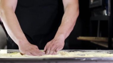İtalyan bir aşçının elinde çiğ hamur profesyonel bir mutfakta İtalyan pizzası yapmak için un ile hamur hazırlıyor..