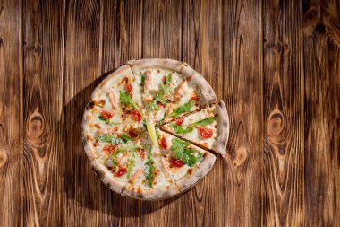 Pizza with salmon, mozzarella, cherry tomatoes, arugula, lemon and parmesan. Italian cuisine on a woden background.