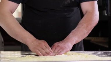 İtalyan bir aşçının elinde çiğ hamur profesyonel bir mutfakta İtalyan pizzası yapmak için un ile hamur hazırlıyor.