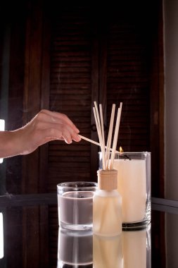 A woman's hand lights scented candles with a match. Romantic dinner. On a dark background. Vertical video