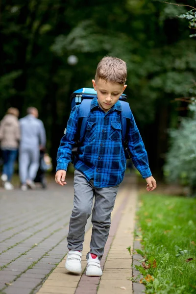 青いバックパックを持つ学校の年齢の男の子は公園で学校に行きます — ストック写真