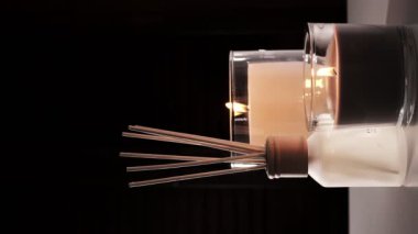Air freshener in a glass bottle and scented candles in candle holders. Home atmosphere. Fragrances for the home. Vertical video.