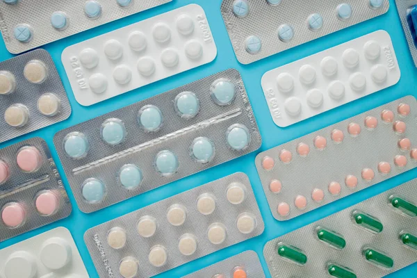 Pharmaceutical drugs, antibiotics, pills. Colorful pills on a blue background, capsule pills.