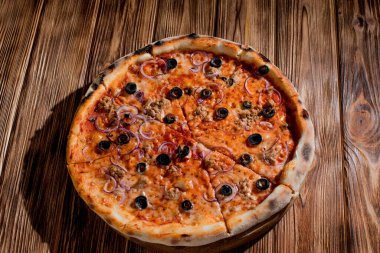 Pizza with tuna, olives, onions, mozzarella cheese and tomato sauce on wood background. Top view, copy space.