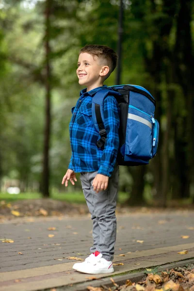 学龄儿童背着蓝色的背包在公园里上学 — 图库照片