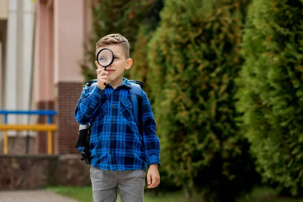 Koulupoika Katselee Suurennuslasin Läpi Yllättynyt Ilme Siristäen Silmiään — kuvapankkivalokuva
