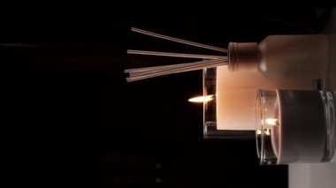 Air freshener in a glass bottle and scented candles in candle holders. Home atmosphere. Fragrances for the home. Vertical video
