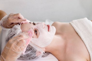 Kırışıklık önleyici nemlendirici maskeli kadın. Bir kadın uzanıyor, güzellik salonunda dinleniyor. Evde ya da kozmetoloji merkezinde SPA prosedürleri.