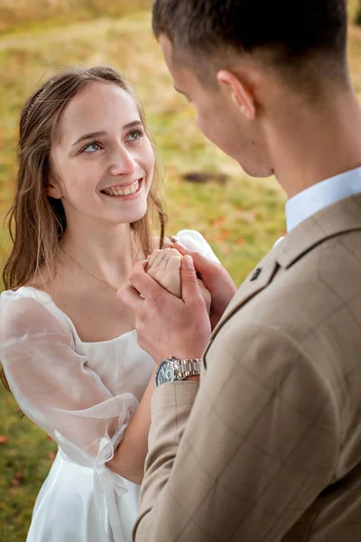 The bride looks at the groom with loving eyes. Smiling newlyweds look into each other\'s eyes