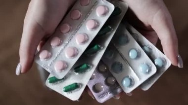 Kadın eli çöp kutusuna bir sürü hap atıyor. Süresi dolmuş haplar. İlaç almayı reddediyor..