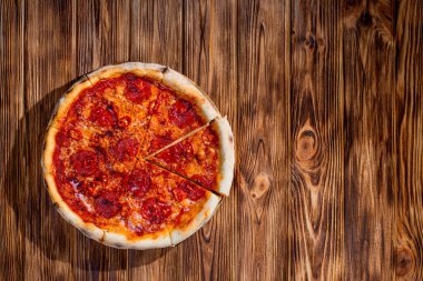 Domates soslu pizza, mozzarella, salam, kırmızı biber, ahşap kaplama bal. Yukarıdan görüntüle, boşluğu kopyala.